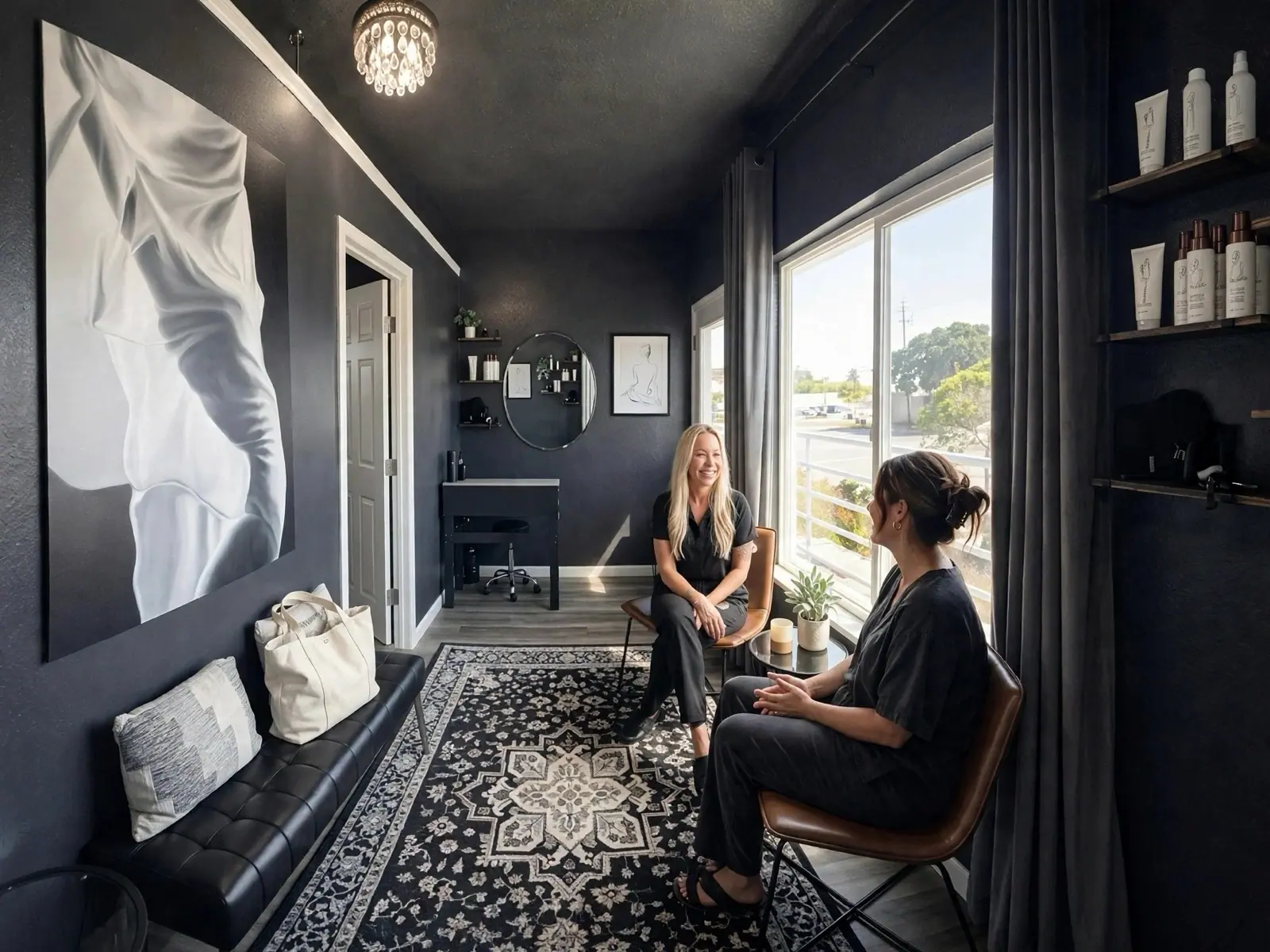 Jana and a client talk before the appointment in the charcoal-walled studio by its big window