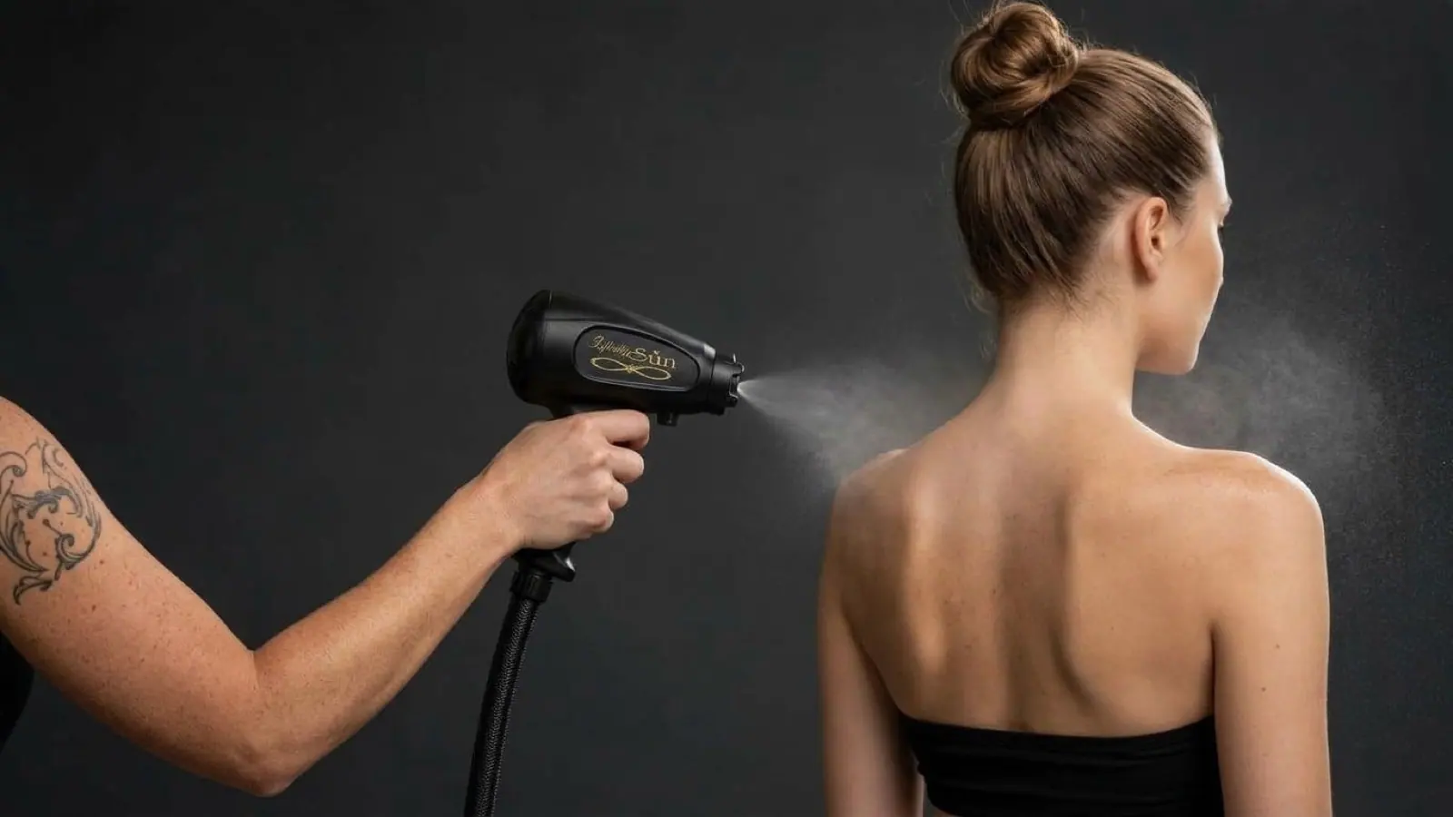 A technician sprays a fine mist across a client's shoulders against a dark studio wall